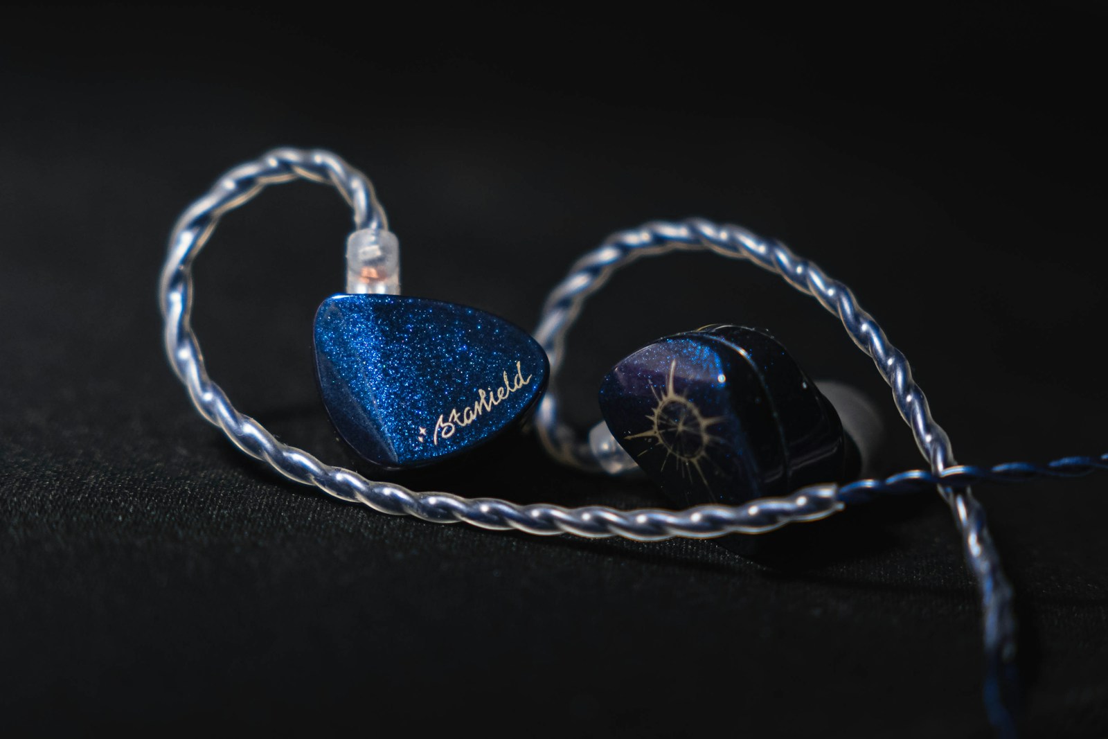 Écouteurs intra-auriculaires (IEM) bleus sur fond noir — illustration pour le guide des technologies de drivers IEM en gaming